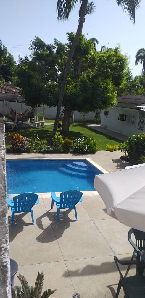 Patio con piscina, sillas y zona de hamacas